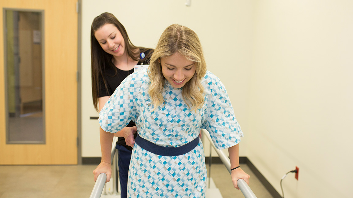 Nurse helps woman in therapy to walk